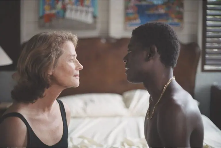 Charlotte Rampling and Ménothy Cesar sit on a bed