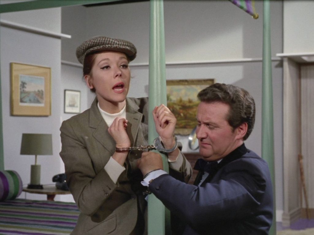 Mrs Peel in handcuffs and John Steed trying to undo them