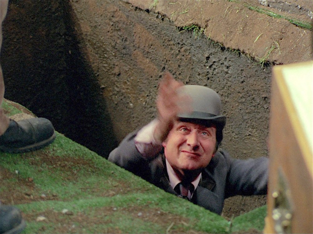 John Steed in a freshly dug grave
