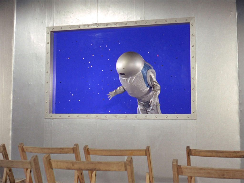 Someone in a space suit floats by the window