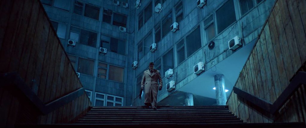A man descends some stairs in a dystopian urban landscape