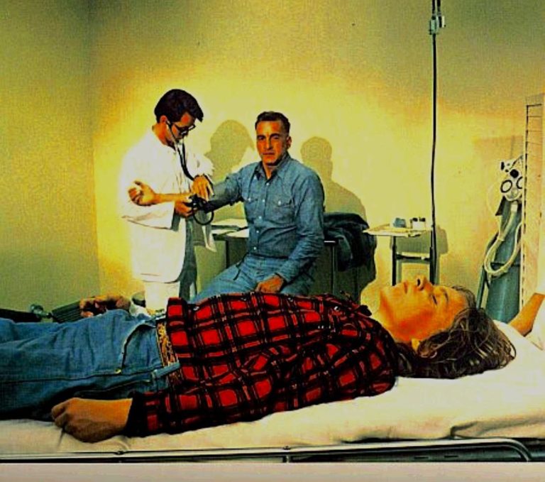 Doctor Holliford checks Dan while son Chris lies on a bed