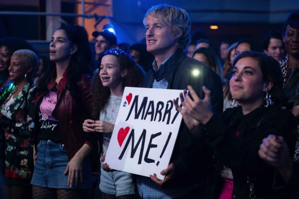 Charlie holds up a sign reading Marry Me