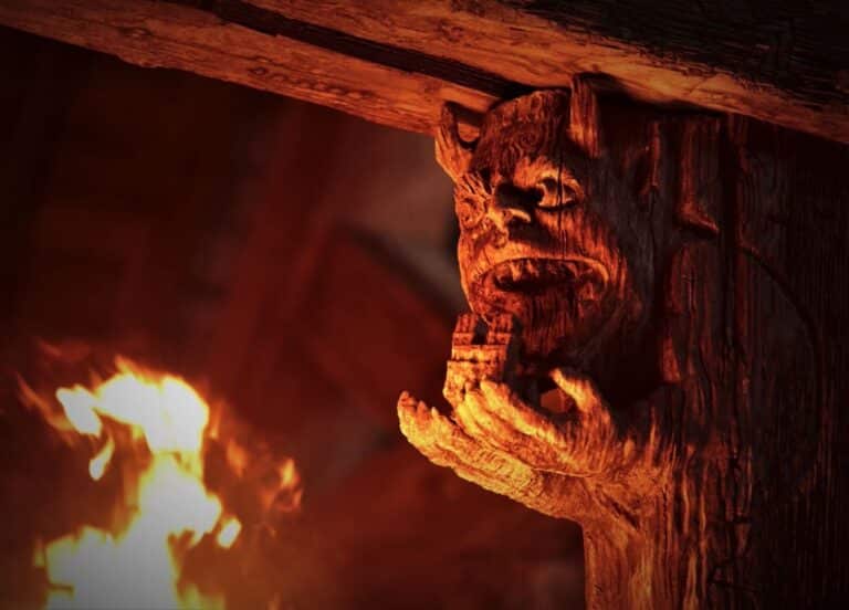 A wooden gargoyle lit up by flames