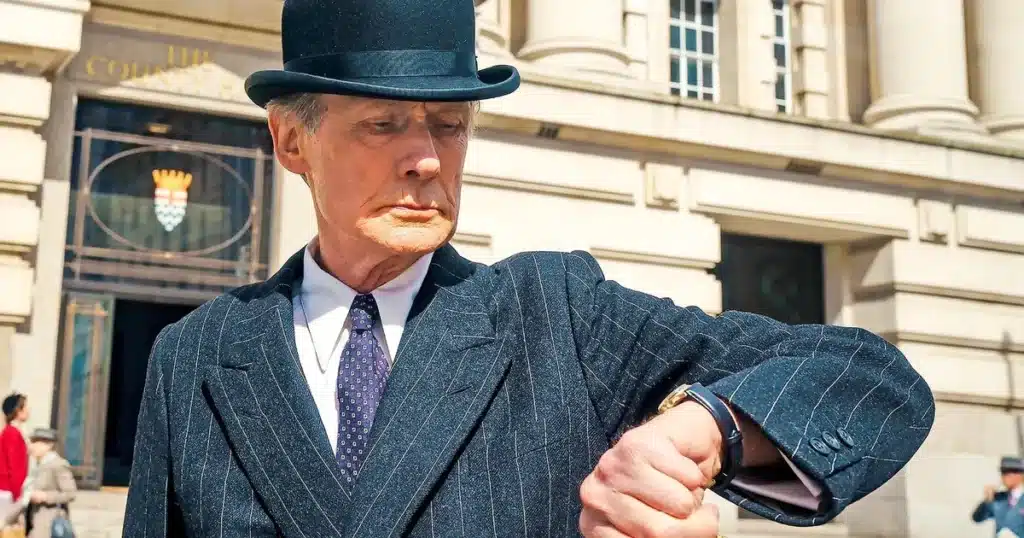 A bowler-hatted Mr Williams checks his watch