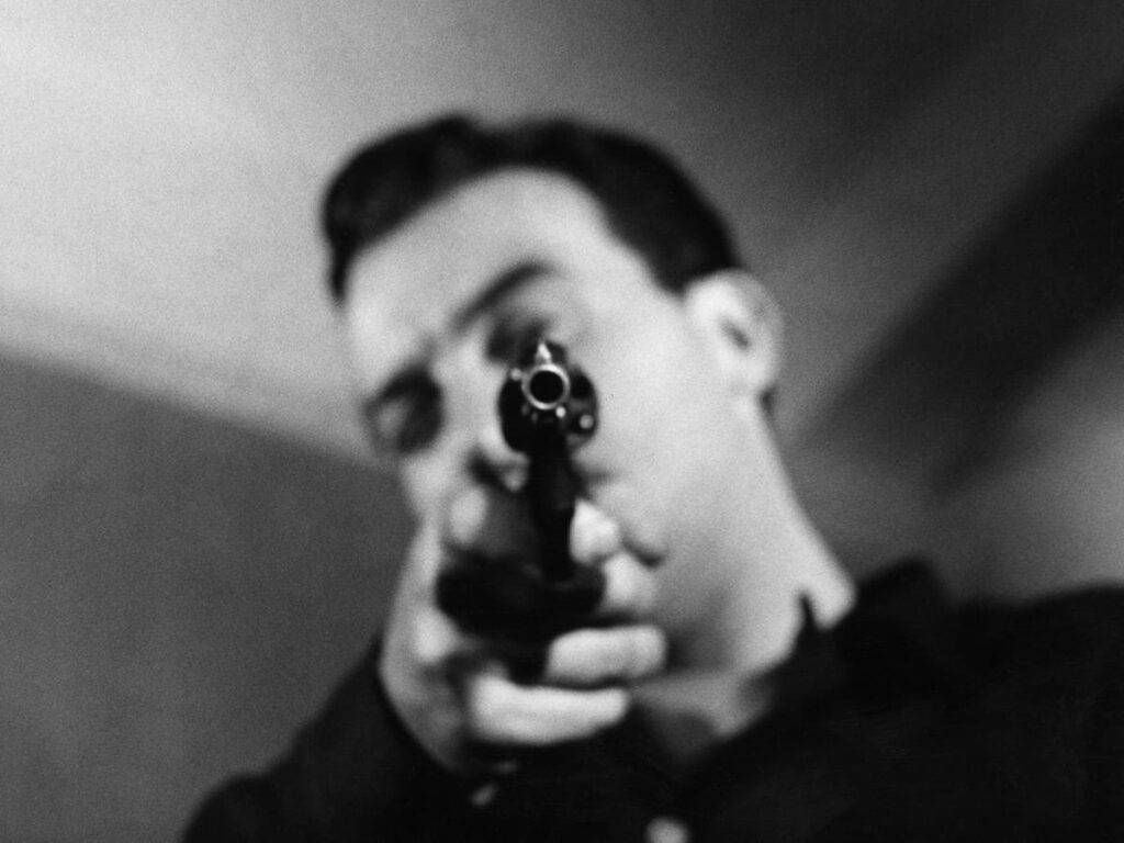 Frank points the gun at the camera