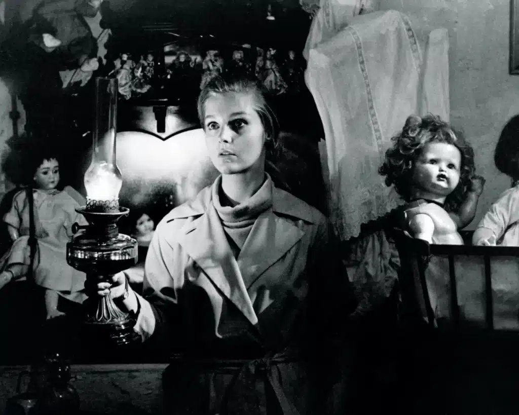 Ann in a toy hospital surrounded by dolls
