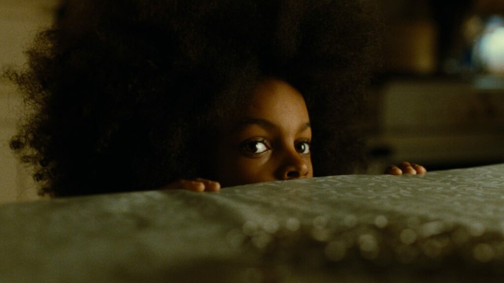 Vicky observes from a hiding place behind a wall