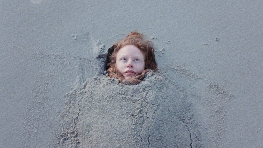Hannah semi-buried on the beach