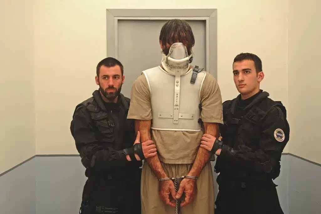 Talan Gwynek restrained with two cops