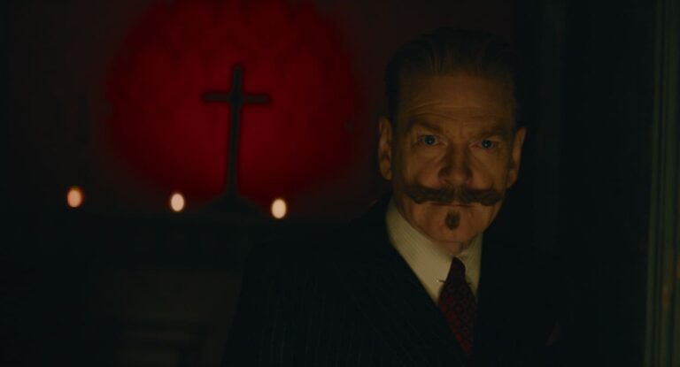 Poirot in the dark with a crucifix in the background
