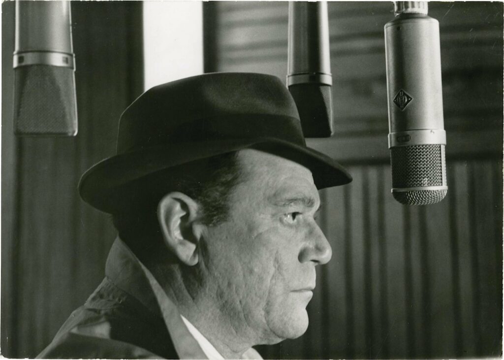 Eddie Constantine in hat and trenchcoat