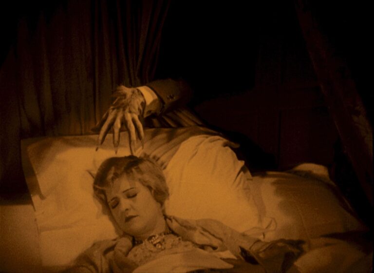 Annabelle in bed with a hand hovering over her