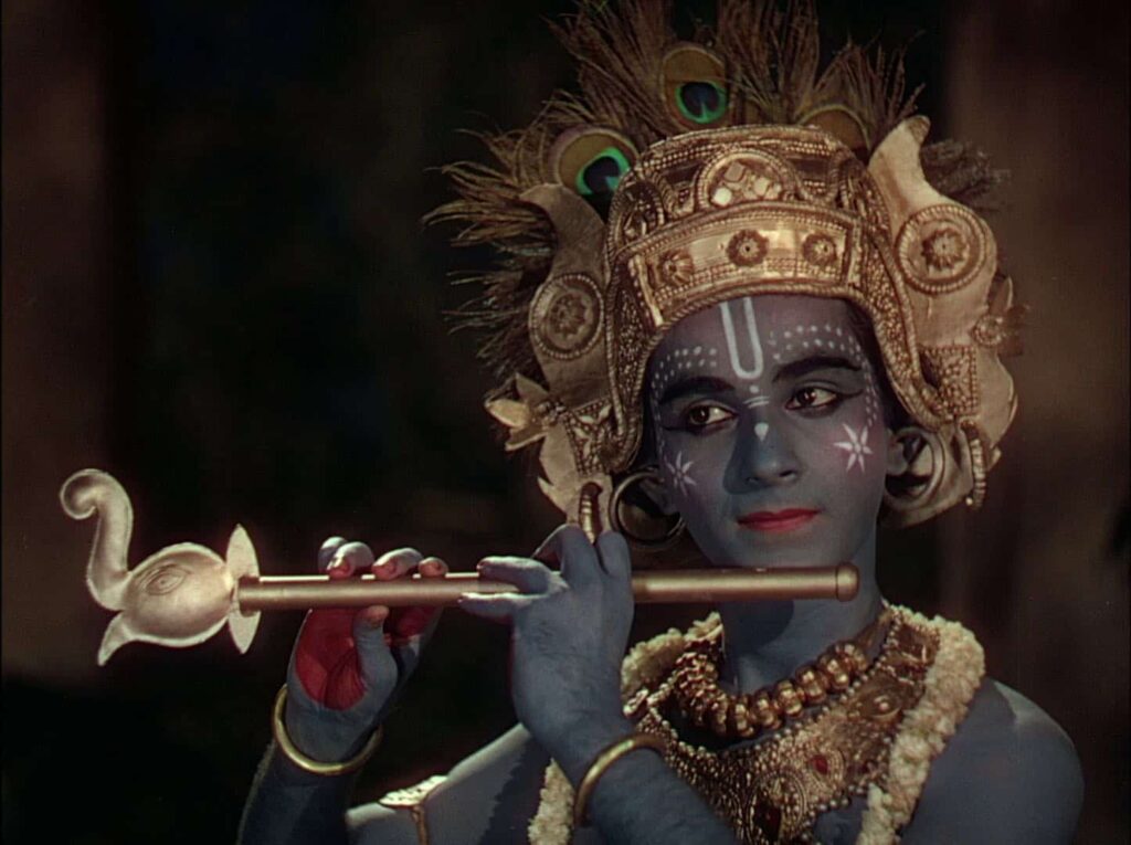 An Indian plays a flute in full ceremonial costume