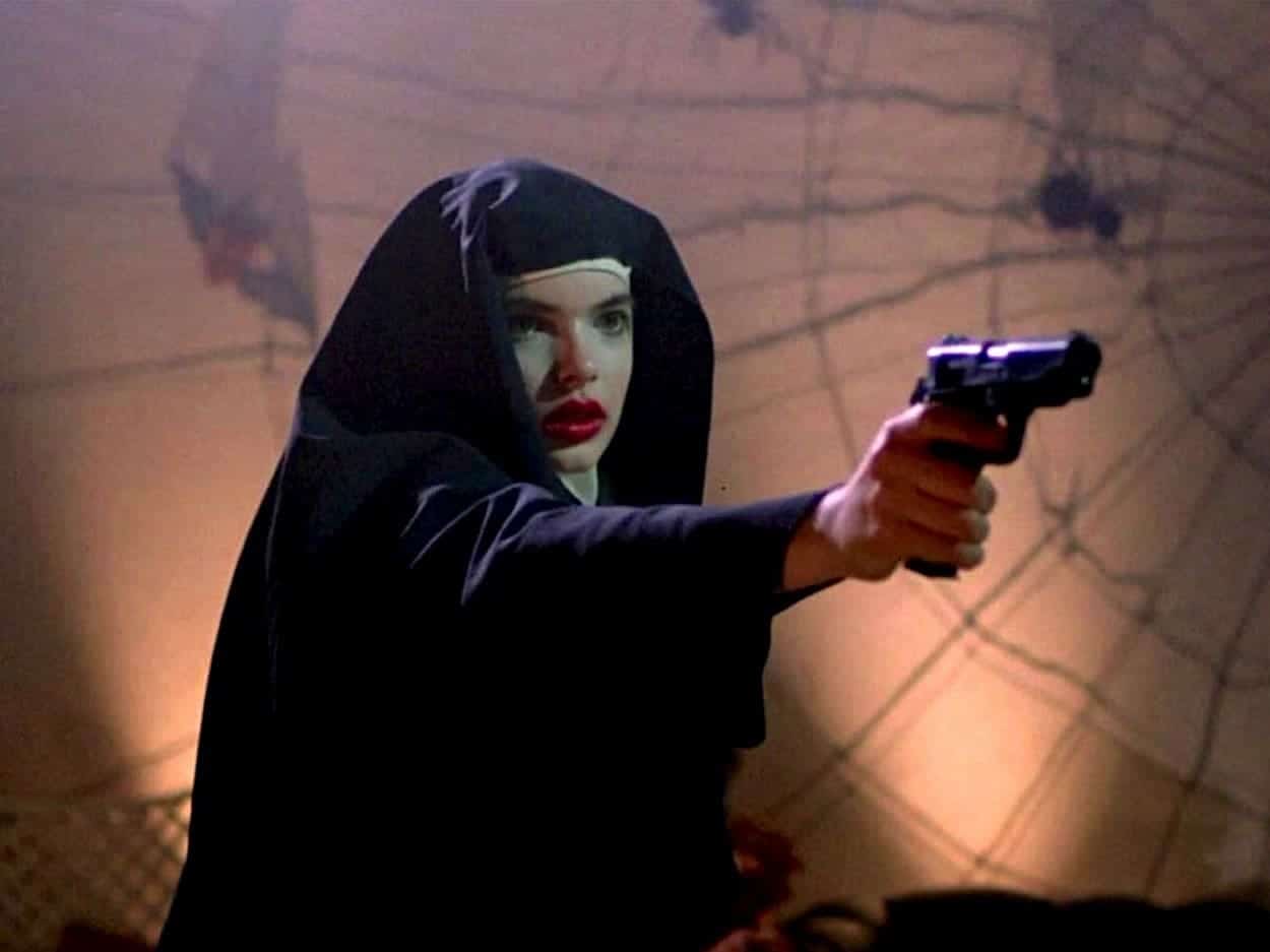 Thana dressed as a nun, with a gun