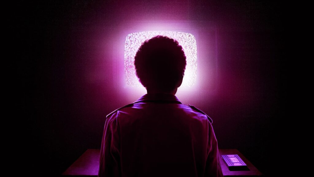 Silhouette of someone watching a glowing TV