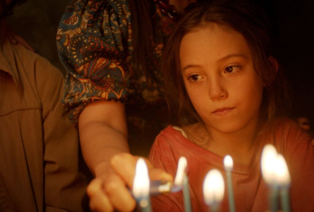 Sol looks on while her dad's birthday cake candles are lit