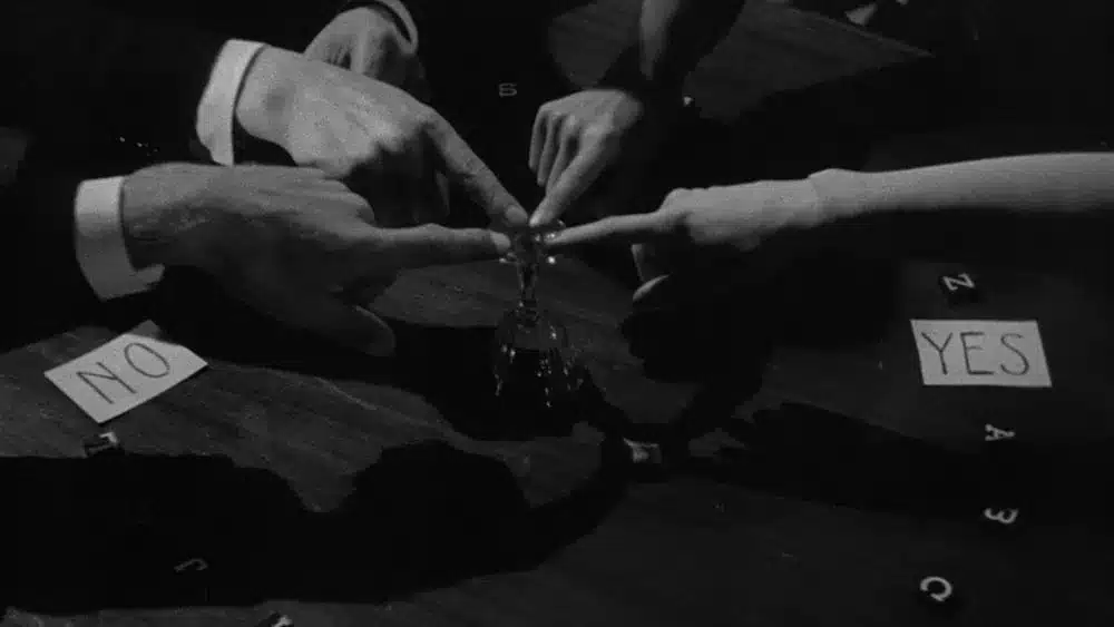 Fingers all touching a glass in a seance