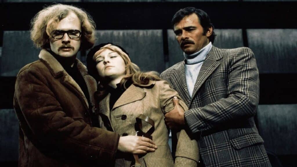 An unconscious Christa is held up by two men