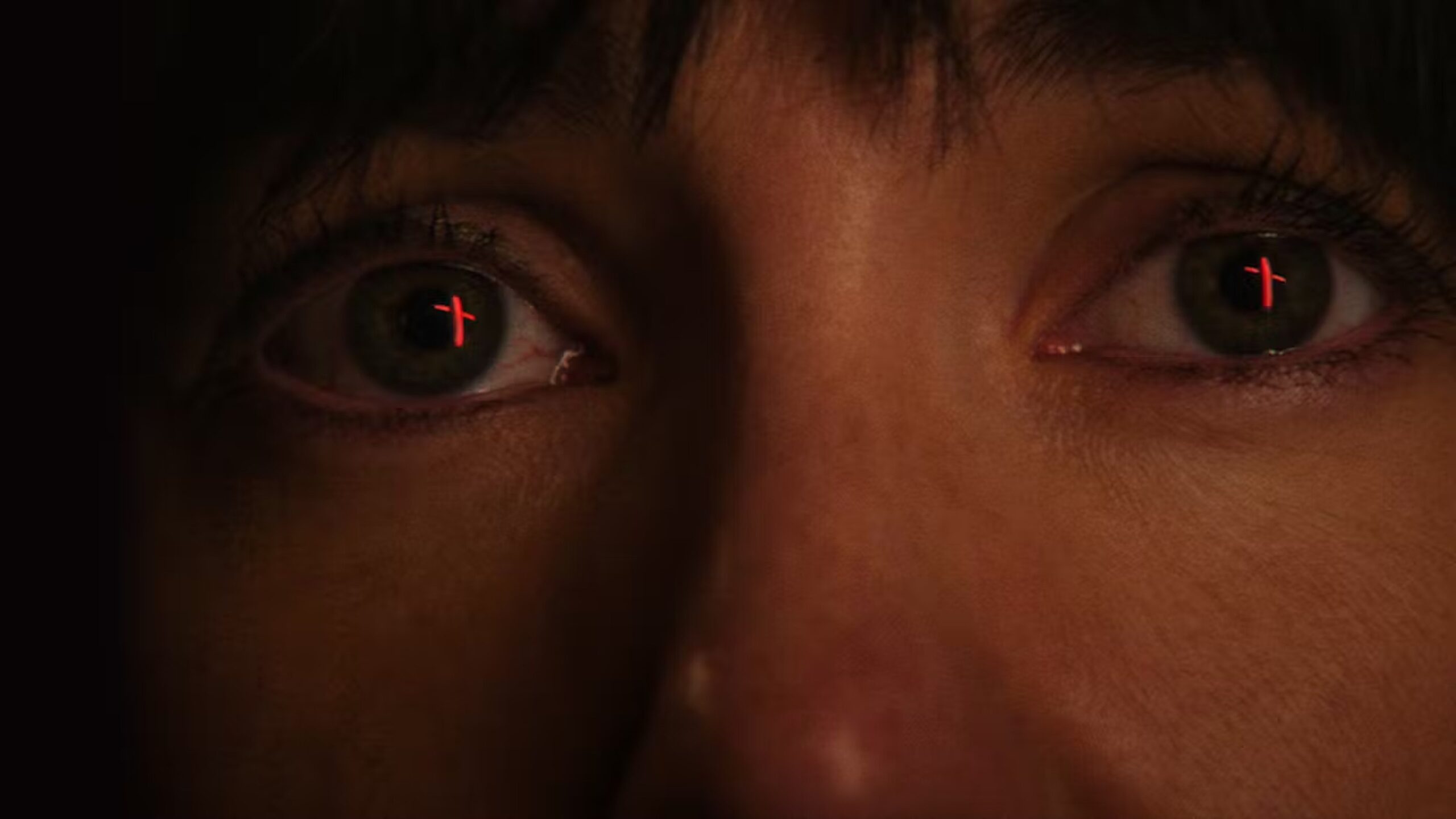 Close up of Shoo's face with red crucifixes reflected