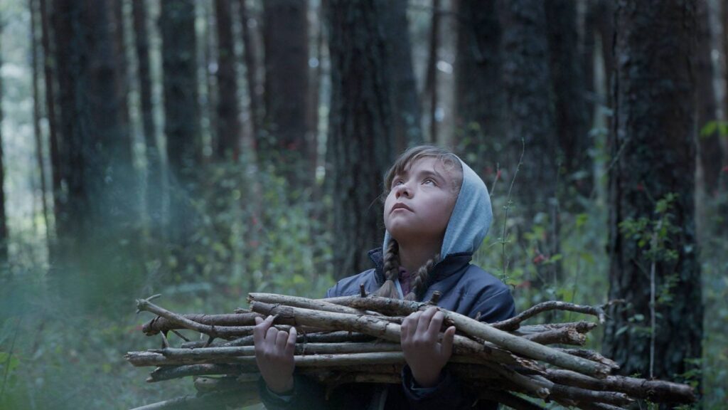 A girl collects kindling in the forest