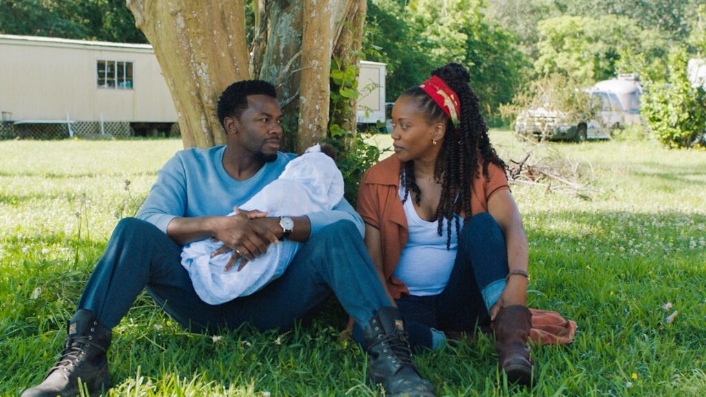 Greg holds the baby while talking to Helen under a tree