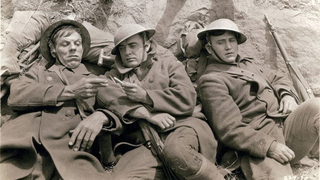 Slim, James and Bull share a cigarette in a trench