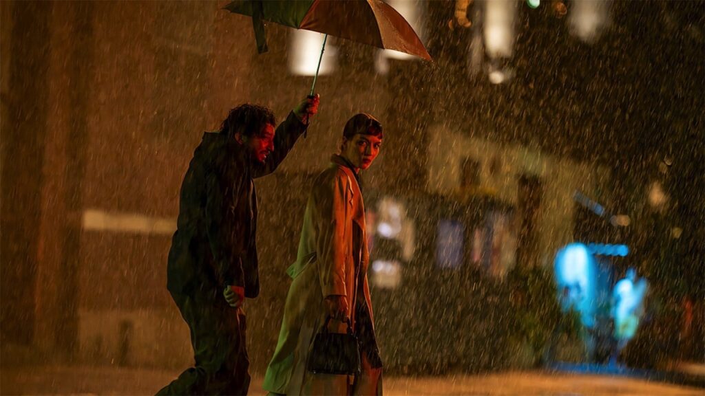 Keane holds an umbrella over Suzie in the rain