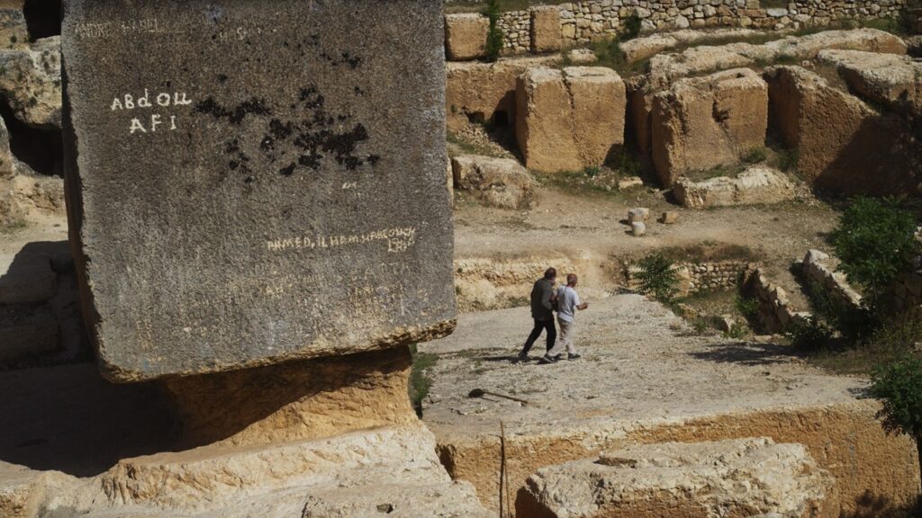 Two men dwarfed by massive stone blocks