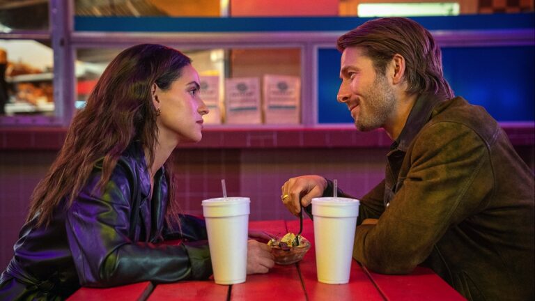 Adria Arjona and Glen Powell facing each other