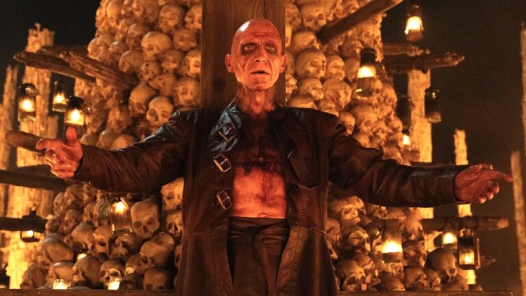 Dr Kelson in front of a stack of skulls