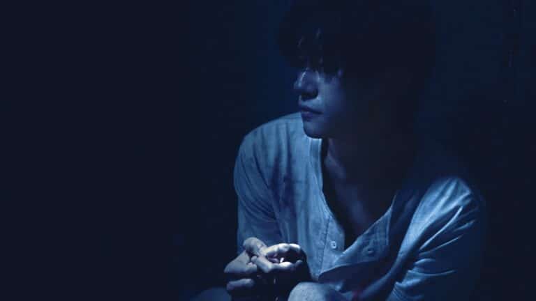 Moody shot of Jackson Yee almost enveloped in shadow