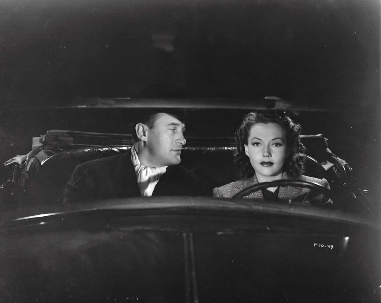 George Sanders and Lynn Bari in an open top car