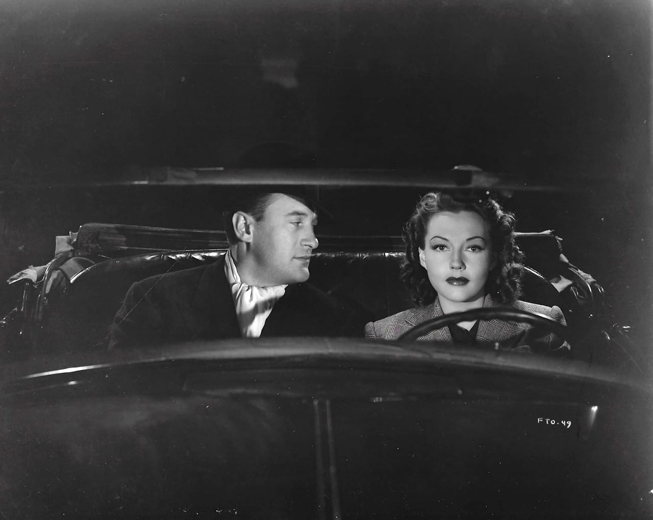 George Sanders and Lynn Bari in an open top car