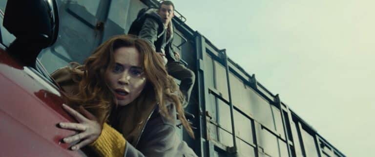 Emily Blunt hangs off a car, with Josh O'Connor trying to save her